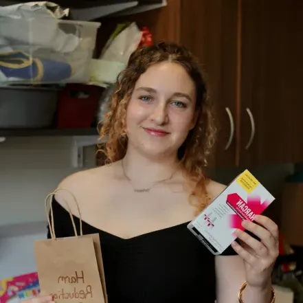 Cailin Young ‘24 prepares a harm reduction bag in the Schacht Center, holding up Narcan and smiling